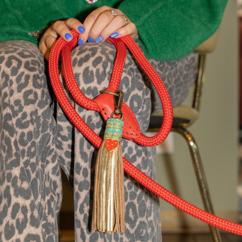 De rode Red Velvet hondenriem (maat L) in gebruik; een luxe handgemaakte riem met een opvallende gouden tassel die perfect past bij een gedurfde DWAM-stijl.