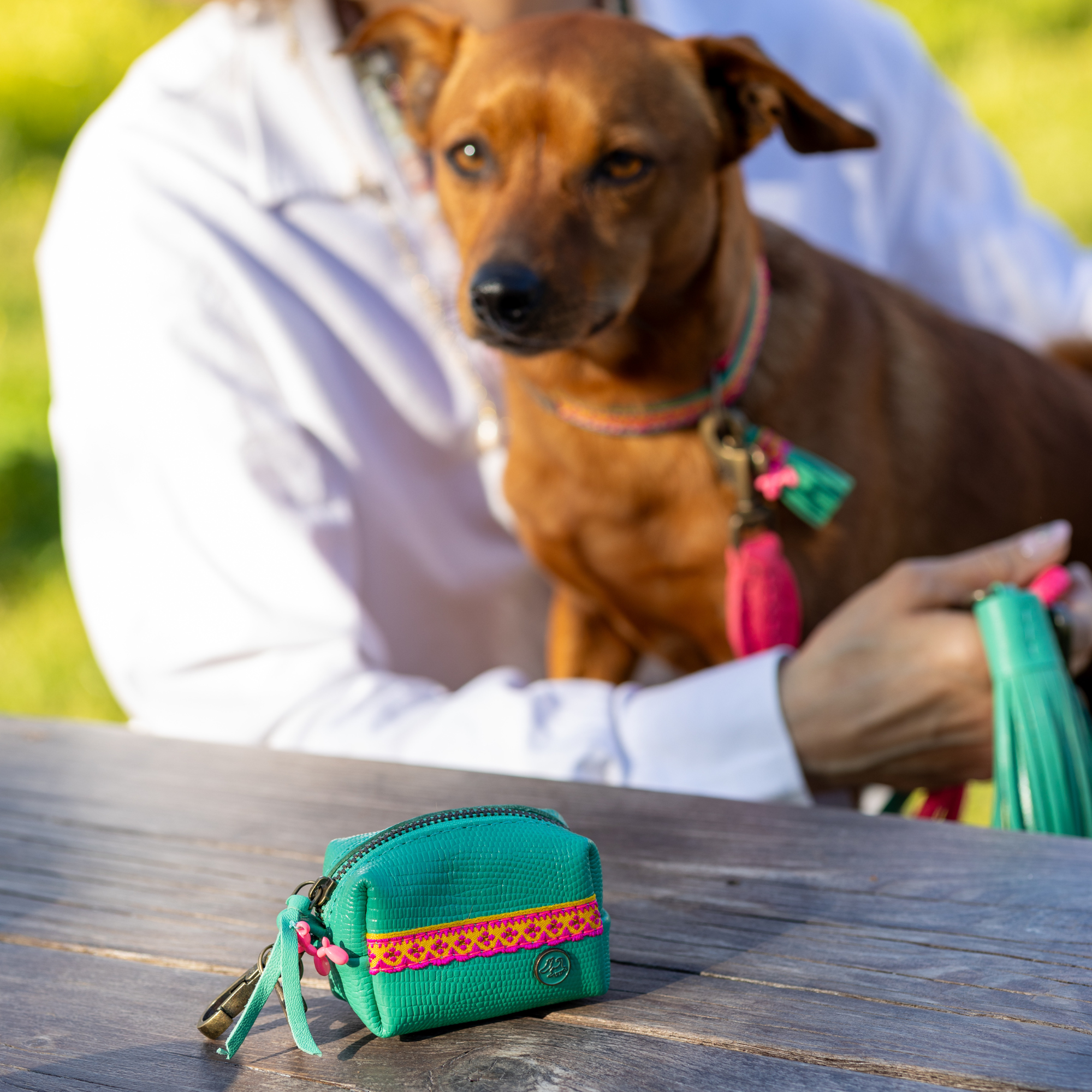 Maui poepzakjeshouder van turquoise buffelleer met felroze voering en boho kwastdetails – handgemaakt door Dog with a Mission

