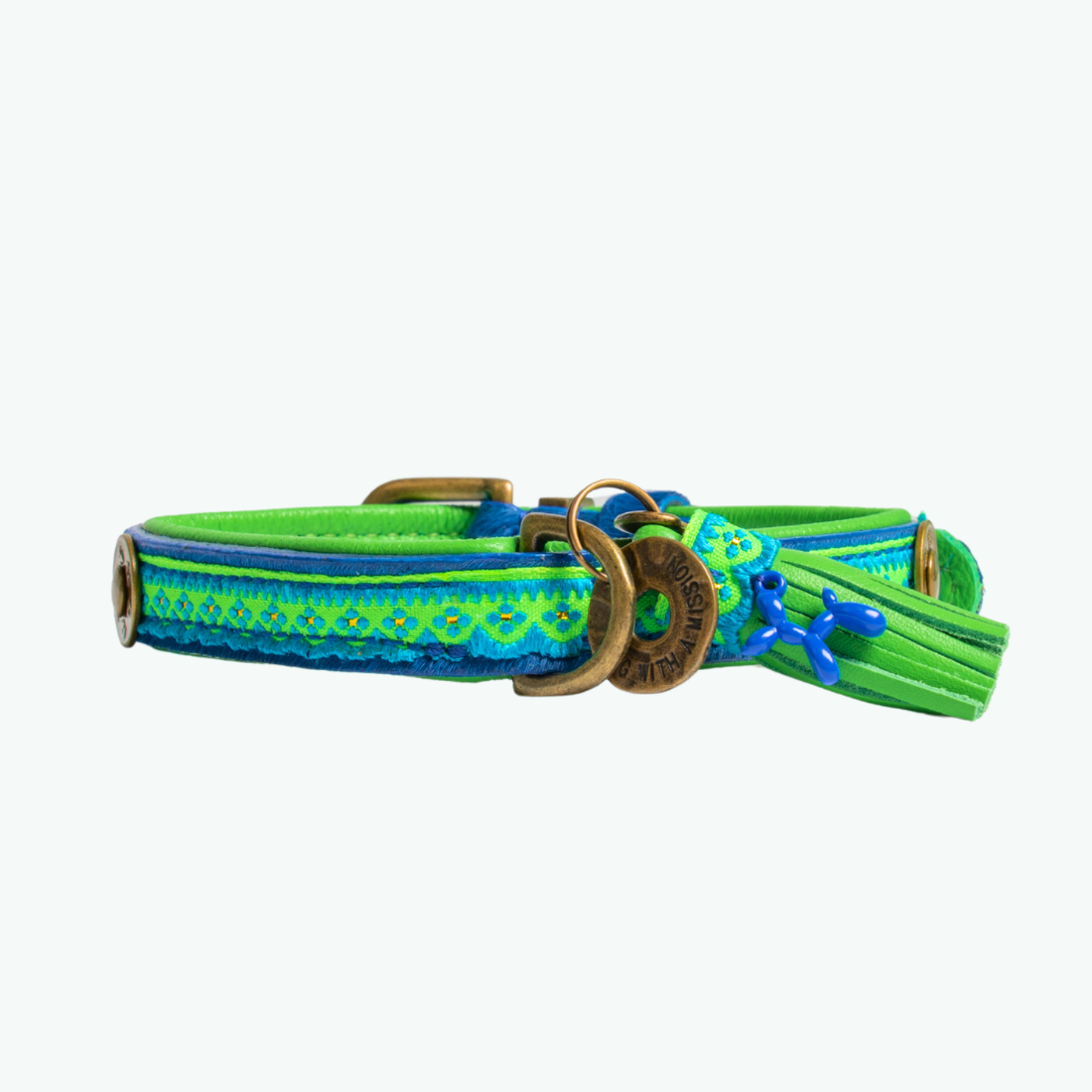 Zula hondenhalsband plat op witte achtergrond, kobaltblauwe vacht met felgroene leren voering en bohemian band, bronzen gesp en DWAM tag, groen leren kwastje met blauwe details